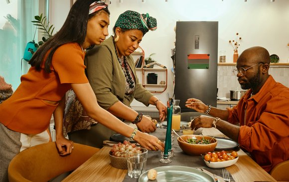 A girl and her two parents prepare food in the kitchen.