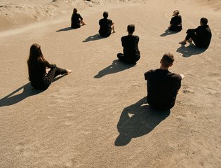A group of young people sit in a desert.