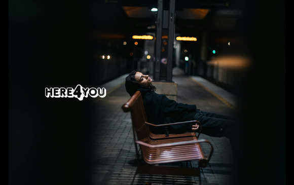 A young person sits on a train station bench alone.