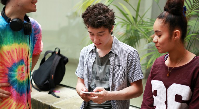 A young girl hugs a cat with a cup of tea.