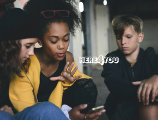 A group of young people look at a phone.