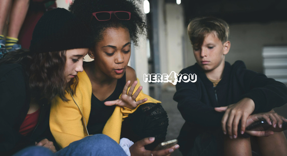 A group of young people look at a phone.