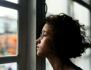 A young person looks out a classroom window.