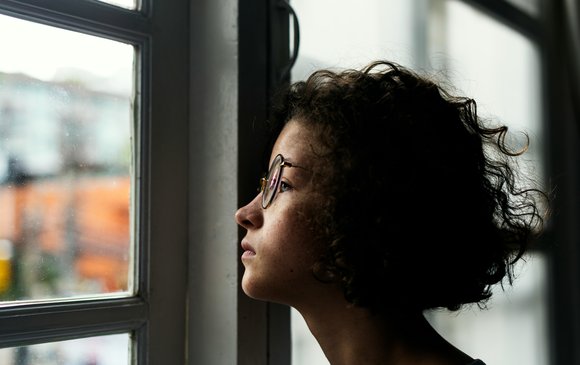 A young person looks out a classroom window.