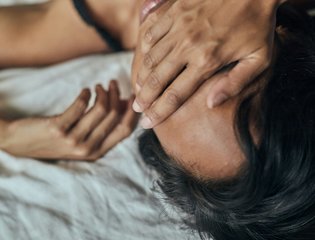 A young person holds their face in their hands.