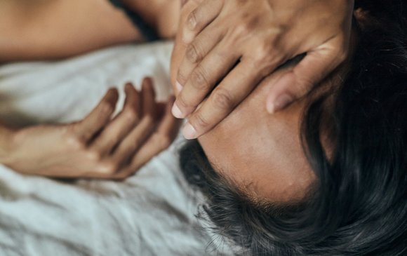 A young person holds their face in their hands.