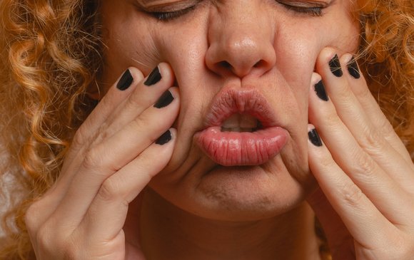 A young woman squeezes her face in disgust.