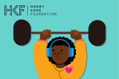 A young person listens to music through their headphones while lifting a weight.